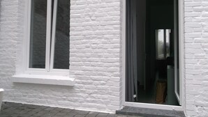 Een wit bakstenen gebouw met een groot raam en een deur die leidt naar een donker interieur.