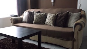 Een woonkamer met een bank, een salontafel en een aan de muur bevestigde televisie.