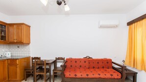 A compact living space with a kitchenette, a sofa, a dining table, and chairs. - Summer Dream II (Naxos)