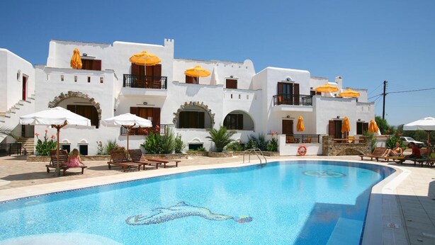 A swimming pool with a dolphin mosaic, surrounded by white buildings with balconies and yellow umbrellas. - Summer Dream II (Naxos)