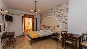 A bedroom with a bed, desk, and chairs, a TV, and a stone-patterned wall. - Summer Dream II (Naxos)