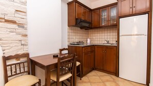 A compact kitchen with wooden cabinets, a built-in microwave, and a white refrigerator. - Summer Dream II (Naxos)