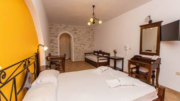A hotel room with a bed, a desk, a chair, a mirror, and a small table.
