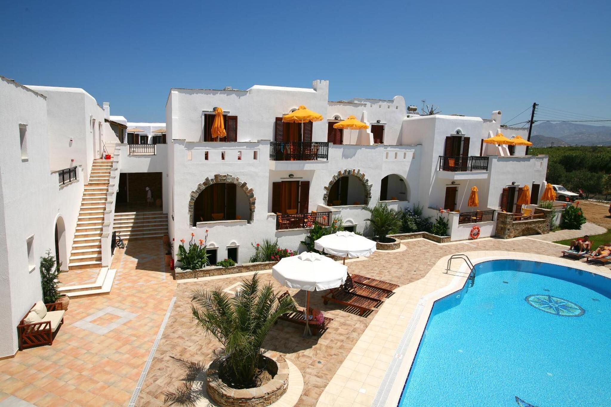 Un resort con piscina, mobiliario exterior y una escalera que lleva a los pisos superiores.