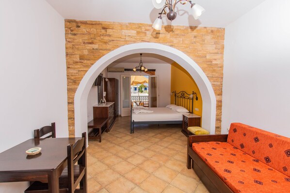 Una habitación con cama, sofá, mesa de comedor y zona de cocina.