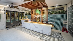 Een hotel receptie met een marmeren balie, plafondventilatoren en een receptieplein.