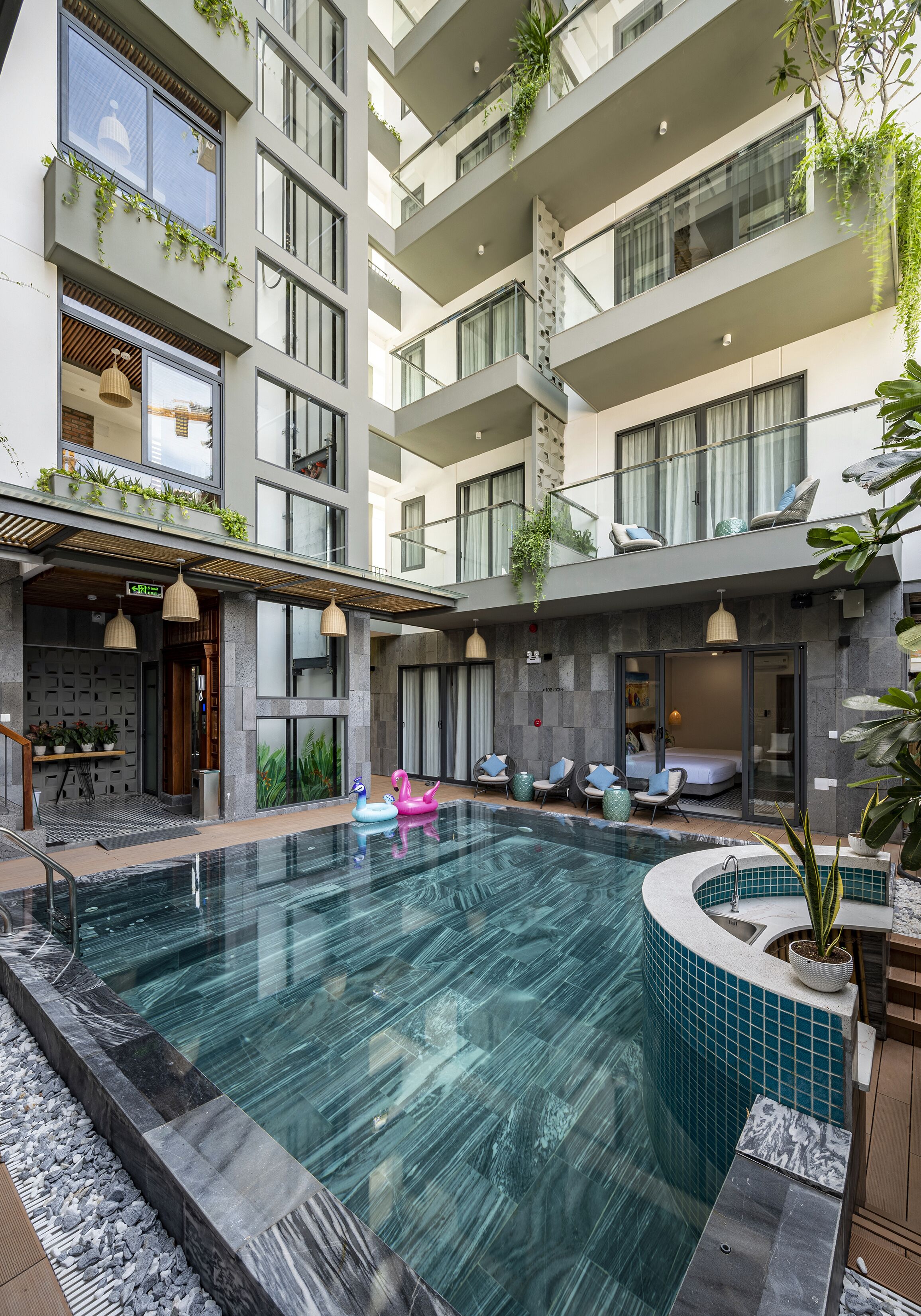 A modern hotel with a rooftop pool, outdoor seating, and a mix of indoor and outdoor spaces.