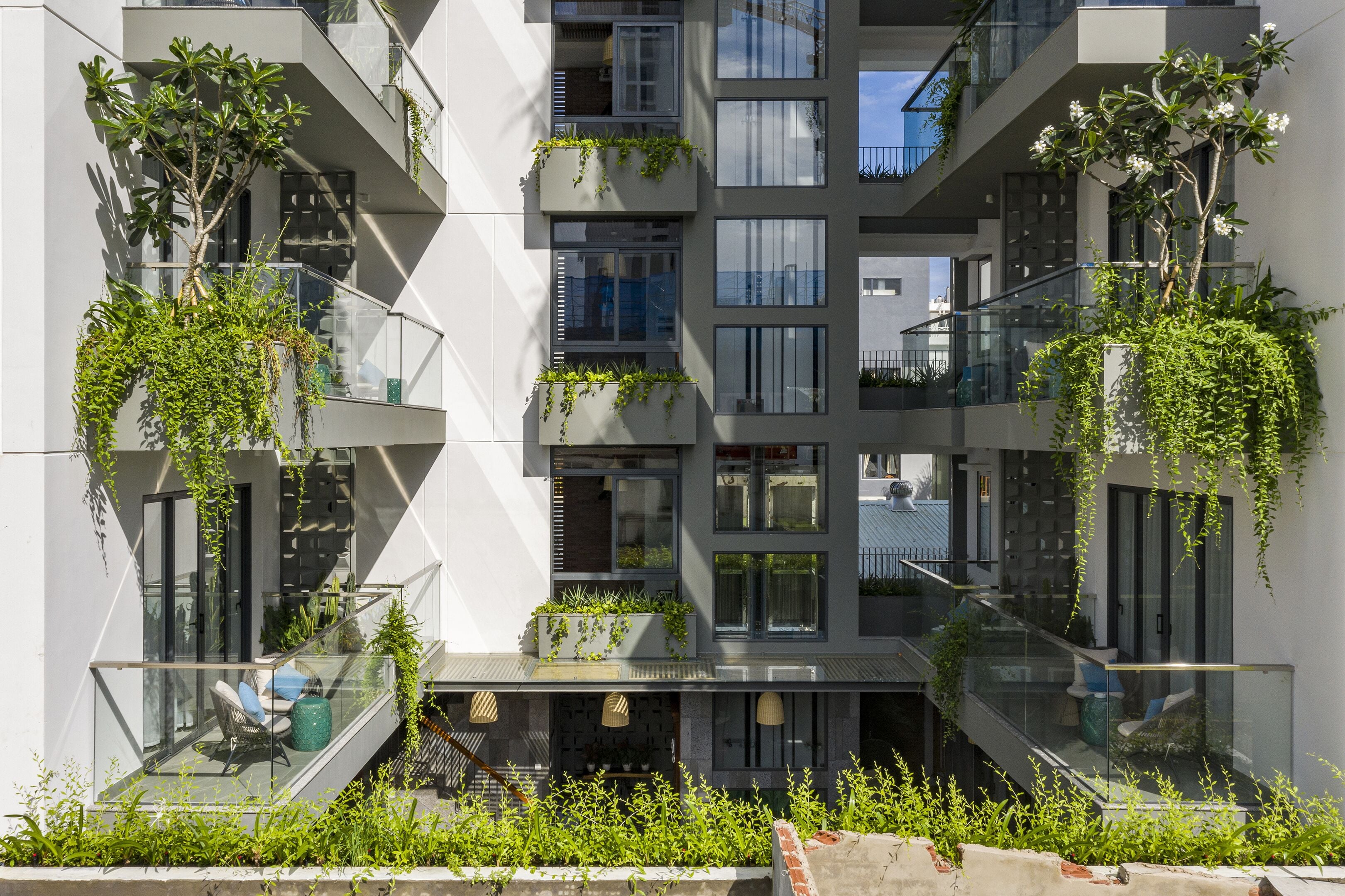 A modern multi-story building with balconies, some with plants.