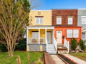 A row of three townhouses with a front porch, a small garden, and a tree. - Gorgeous Home 10 min to DC by CozySuites (Alexandria)