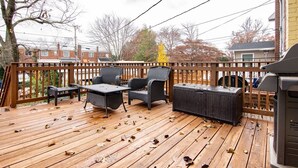 A wooden deck with outdoor furniture, including chairs and a table.