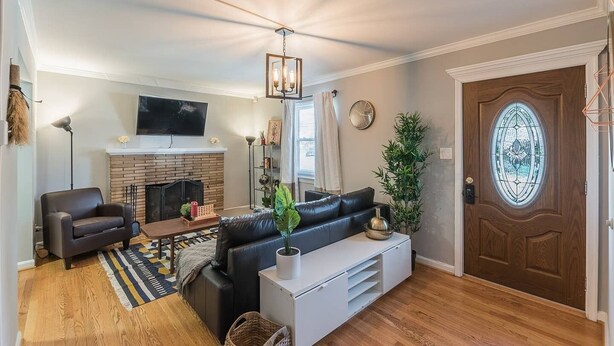 A living room with a fireplace, a sofa, a TV, and a wooden door with a stained glass window. - Enchanting historic townhouse by CozySuites (Alexandria)