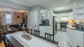 A modern kitchen with white cabinets, a stainless steel refrigerator, and a dining area with a table set for two. - Enchanting historic townhouse by CozySuites (Alexandria)