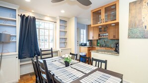 A modern kitchen with wooden cabinets, a built-in oven, and a dining area with a table set for four. - Spacious 4BR CozySuites in Old Town Alexandria (Alexandria)