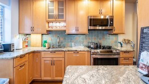 A kitchen with wooden cabinets, a stainless steel microwave, a gas stove, and a granite countertop. - Spacious 4BR CozySuites in Old Town Alexandria (Alexandria)