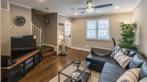A modern living room with a flat-screen TV, leather sofa, and a glass coffee table.