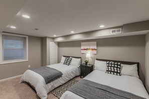 A bedroom with two beds, a nightstand, a lamp, and a cityscape artwork on the wall. - Beautiful 3br/2ba House with cozy backyard by CozySuites (Alexandria)