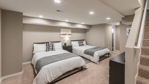 A bedroom with two beds, a staircase, and a ceiling light.