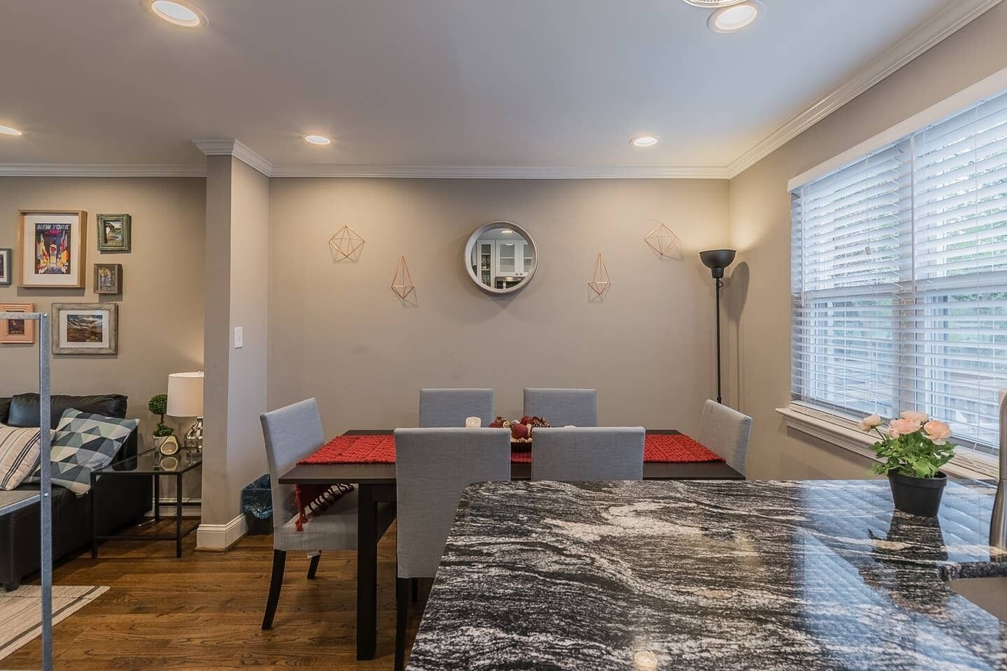 A dining area with a marble table, grey chairs, and a red placemat.