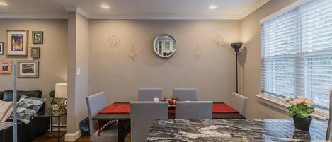 A dining area with a marble table, grey chairs, and a red placemat.