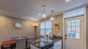 A modern kitchen with a central island, white cabinetry, and a window with blinds.