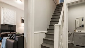 A staircase leading to a bathroom with a toilet paper holder and a sink. - Louisville Dream House 4BR/2BA  by CozySuites (Louisville)