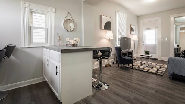 A modern living room with a dining area, a TV, and a small table with a plant. - Louisville Dream House 4BR/2BA  by CozySuites (Louisville)