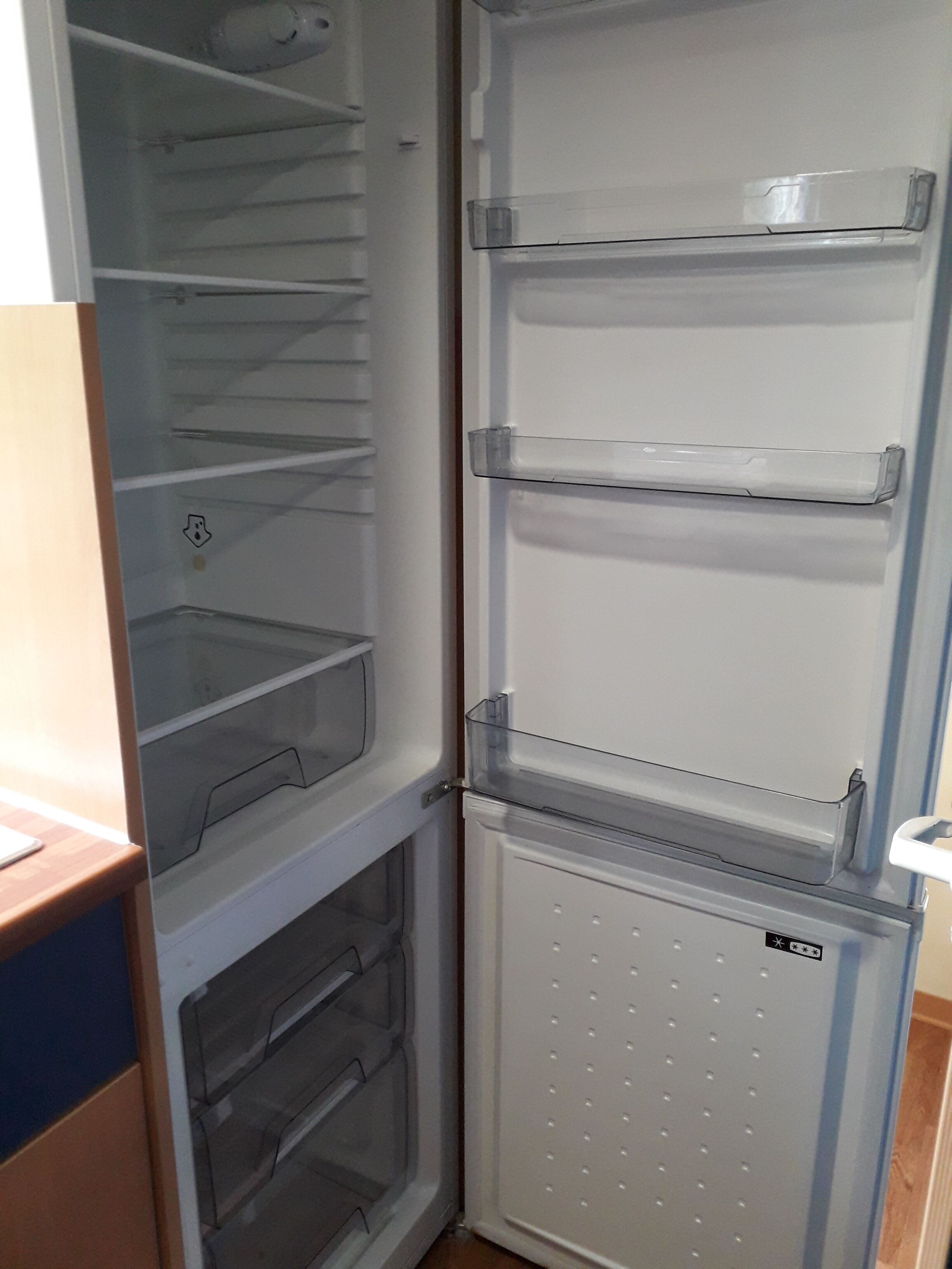 Un refrigerador abierto con varias estantes y cajones.