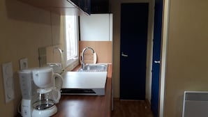 Een kleine keuken met een koffiezetapparaat, een spoelbak en een raam.