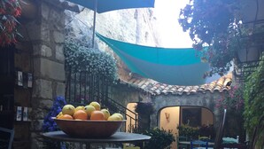 A courtyard with stone walls, a tiled floor, and outdoor seating with tables and chairs.