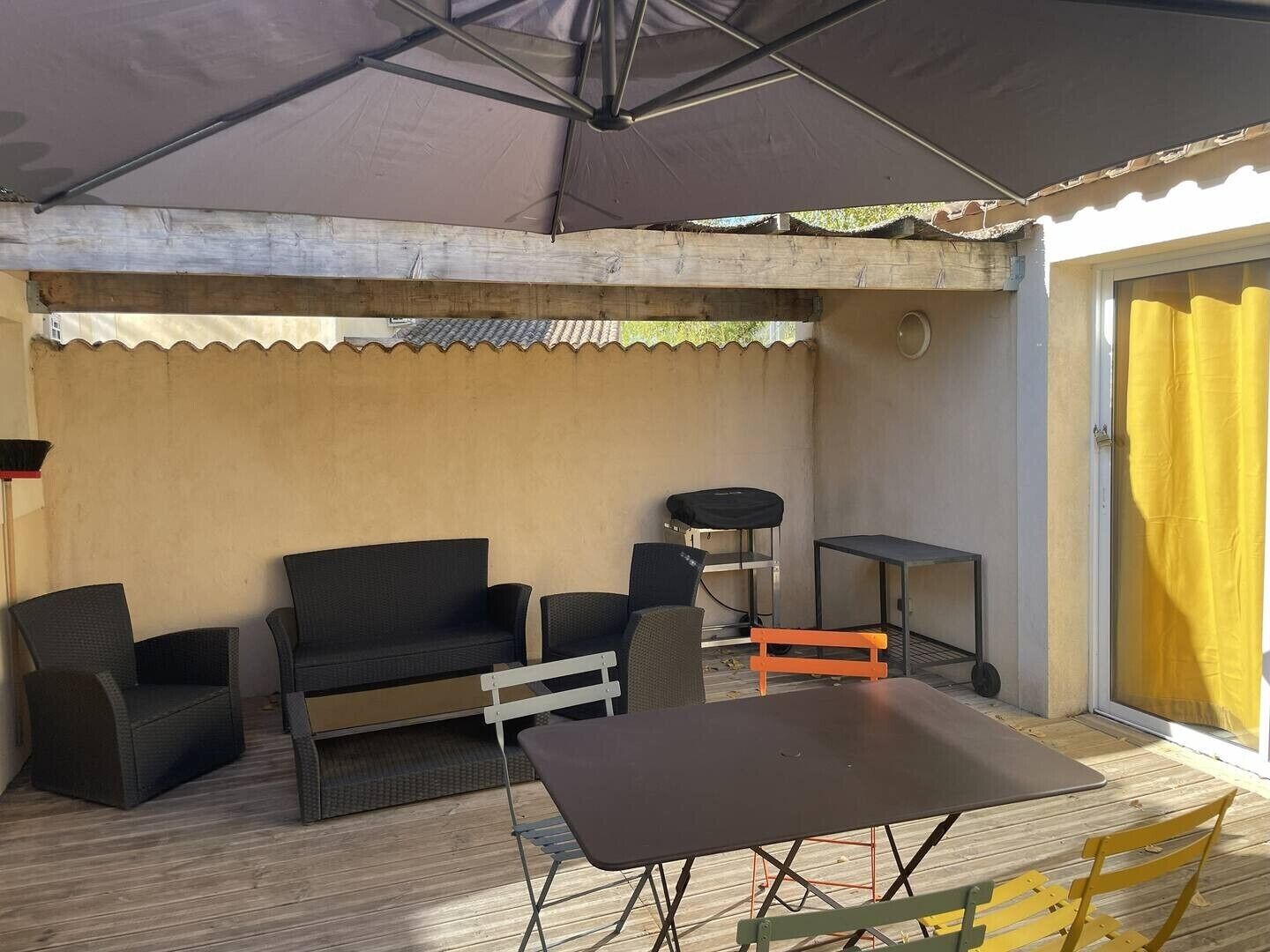 Ein überdachter Patio-Bereich mit Tisch, Stühlen, einer Couch und einem kleinen Tisch.
