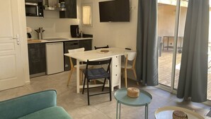 A compact kitchen with modern appliances, a dining area with a table and chairs, and a balcony with a view.
