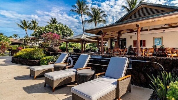 A resort with outdoor seating, palm trees, and a covered area.