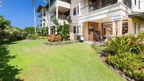 A two-story house with a balcony, a patio with outdoor furniture, and a well-maintained garden.
