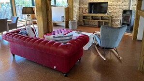 Ein gemütliches Wohnzimmer mit einem roten Sofa, einem blauen Sessel und einem Kamin aus Stein.