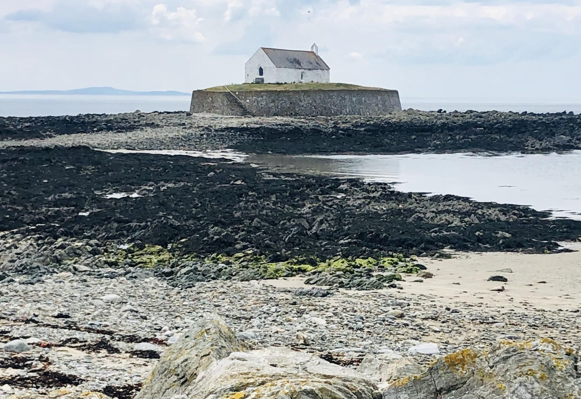 A white building on a rocky shore with a view of the sea.
