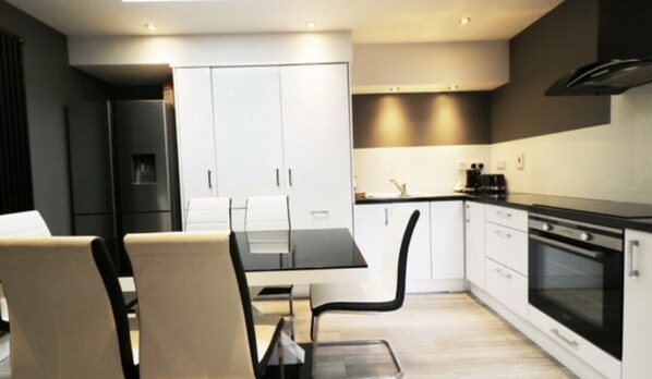 A modern kitchen with white cabinets, a black countertop, and a built-in oven.