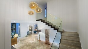 A modern interior with a staircase, a glass railing, and a contemporary light fixture. - Luxurious Villa Amer with Private Pool in Bonaire Alcúdia (Alcúdia)