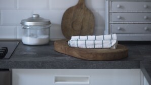 A kitchen with white cabinets, a wooden cutting board, a metal container, and a wooden spoon. - ☸THE SEA HOUSE w / t Sea view  (Livorno)