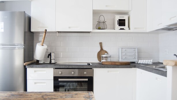 A modern kitchen with white cabinetry, a stainless steel refrigerator, a wooden table, and a hanging pendant light. - ☸THE SEA HOUSE w / t Sea view  (Livorno)
