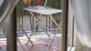 A balcony with a white metal chair and a small round table, a potted plant with pink flowers, and a view of a garden. - ☸THE SEA HOUSE w / t Sea view  (Livorno)