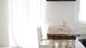 A dining area with a wooden table, white chairs, and a TV mounted on the wall. - ☸THE SEA HOUSE w / t Sea view  (Livorno)