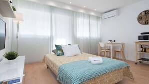 Una habitación de hotel con cama, escritorio, silla y un reloj en la pared.
