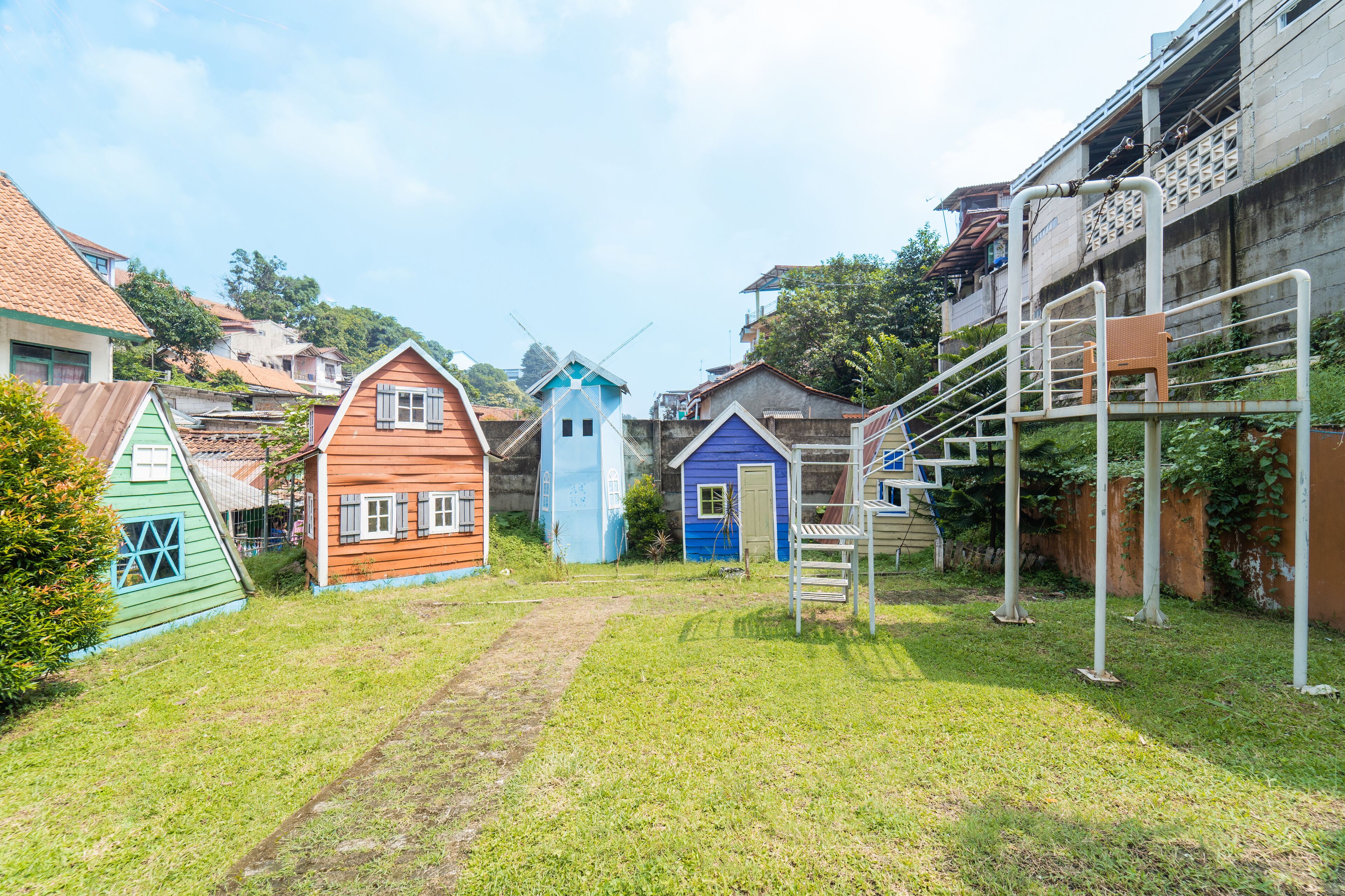 A residential area with colorful houses, a windmill, and a staircase leading to a building.