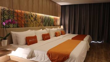 A hotel room with a large bed, a headboard with a floral mural, a potted plant, and a view of the outdoors.