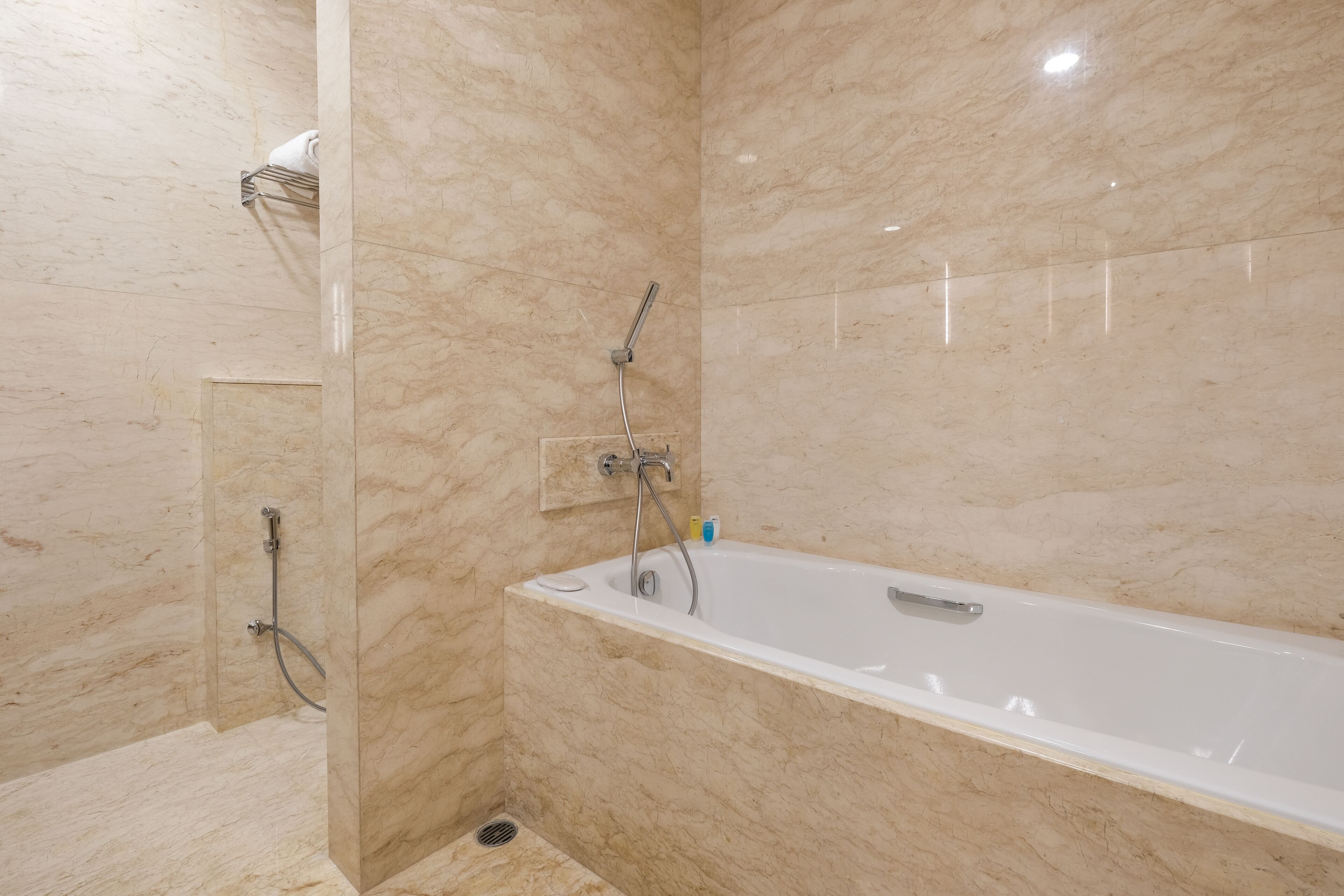 Un baño moderno con una bañera grande, zona de ducha y paredes de mármol.