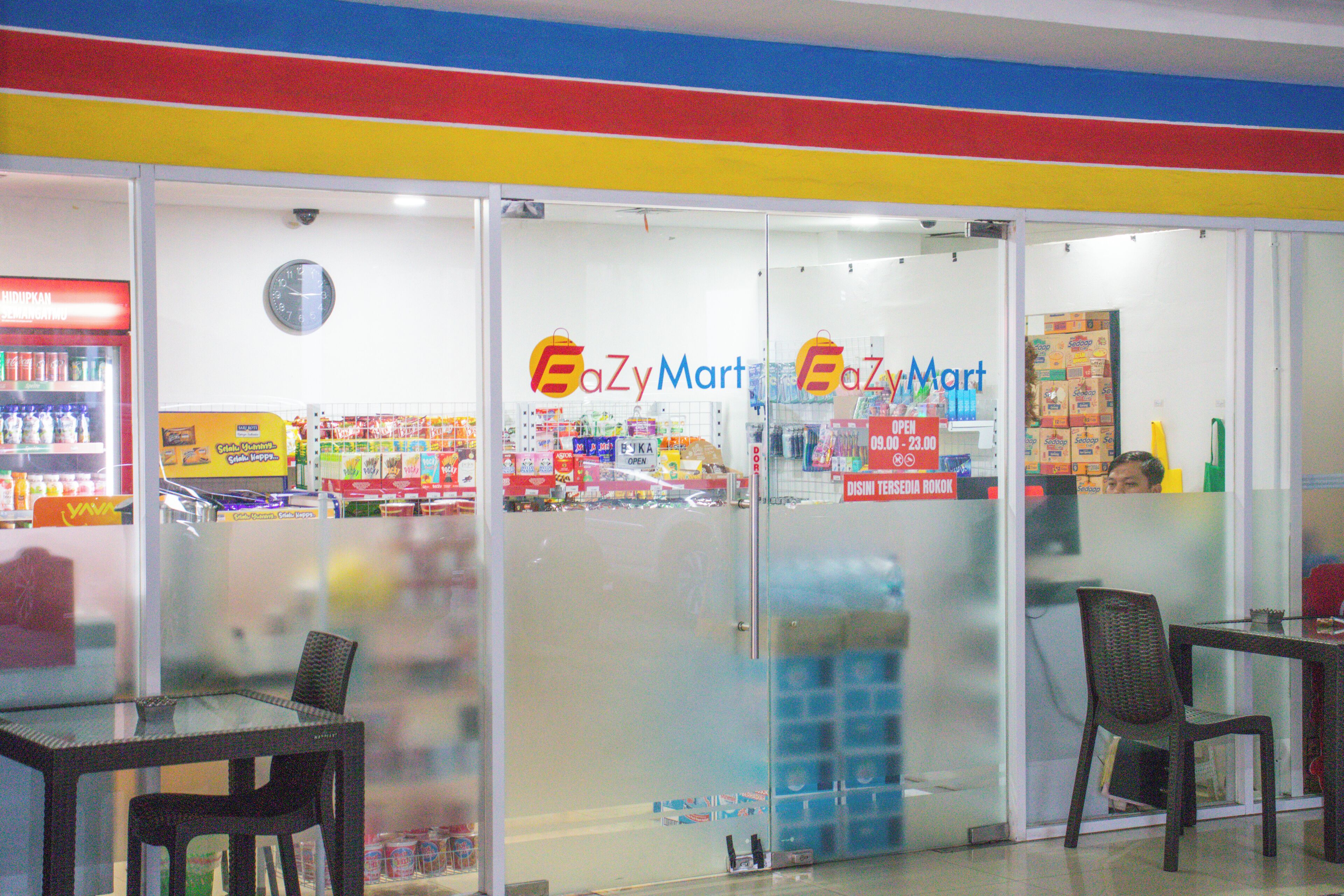 A storefront with a glass facade, a clock on the wall, and a sign that reads 'EaZyMart'.