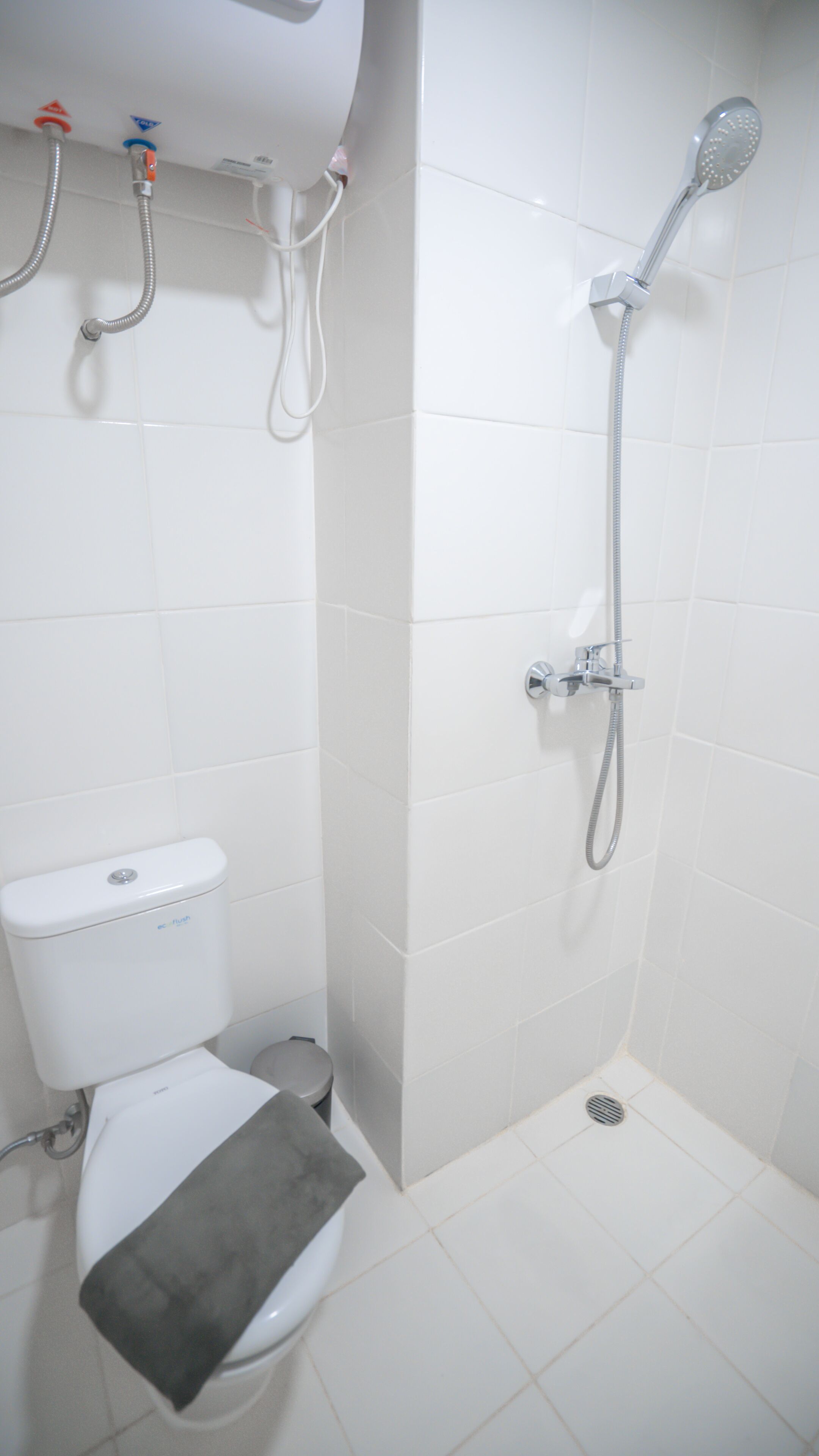 Um banheiro pequeno e branco com vaso sanitário, chuveiro e pia.
