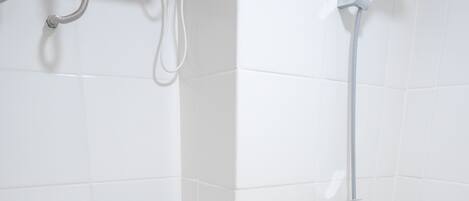 Um banheiro pequeno e branco com vaso sanitário, chuveiro e pia.