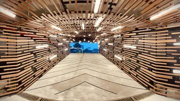 A modern, tunnel-like interior with wooden slats on the walls and ceiling, and a chevron-patterned floor.