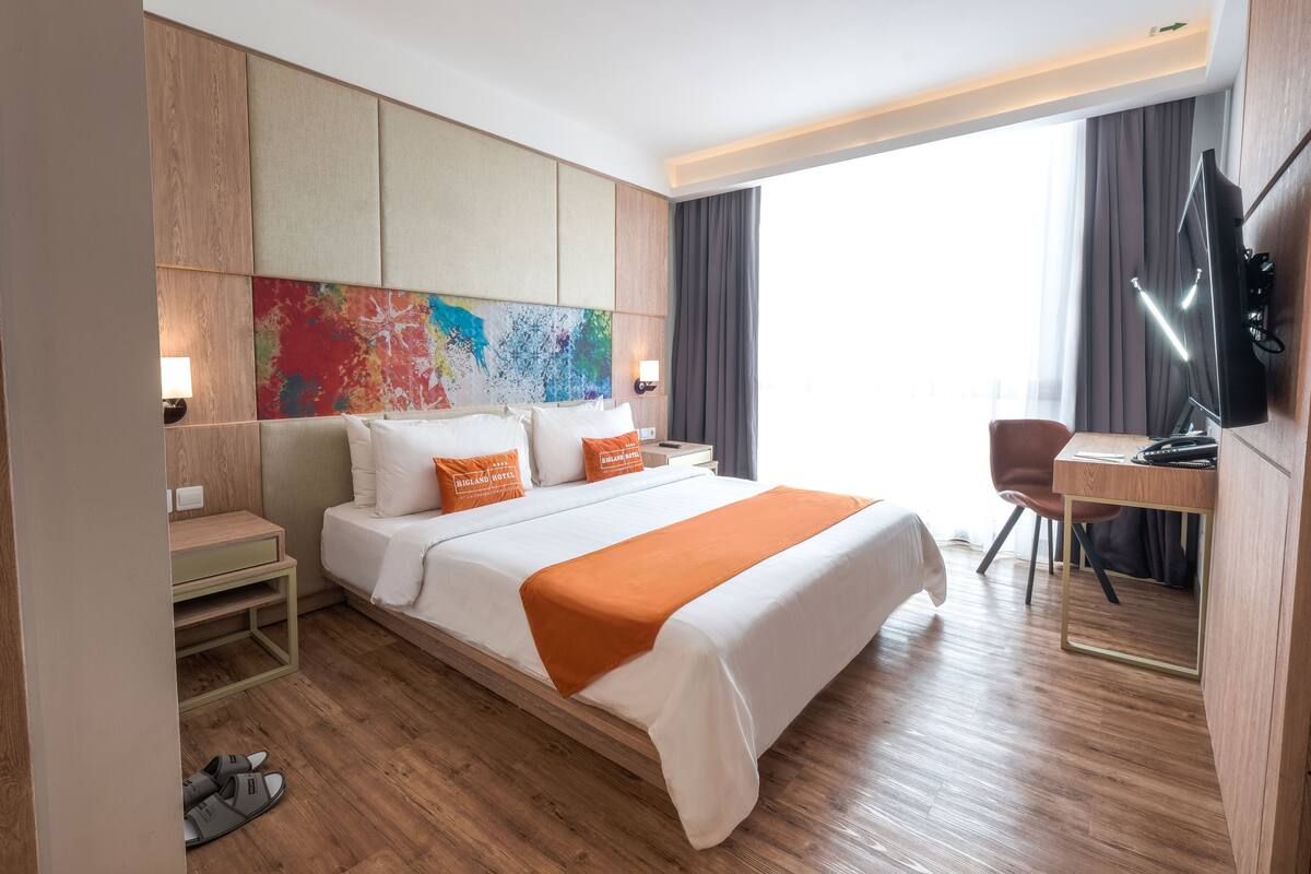 A hotel room with a bed, a desk, a TV, and a large window.